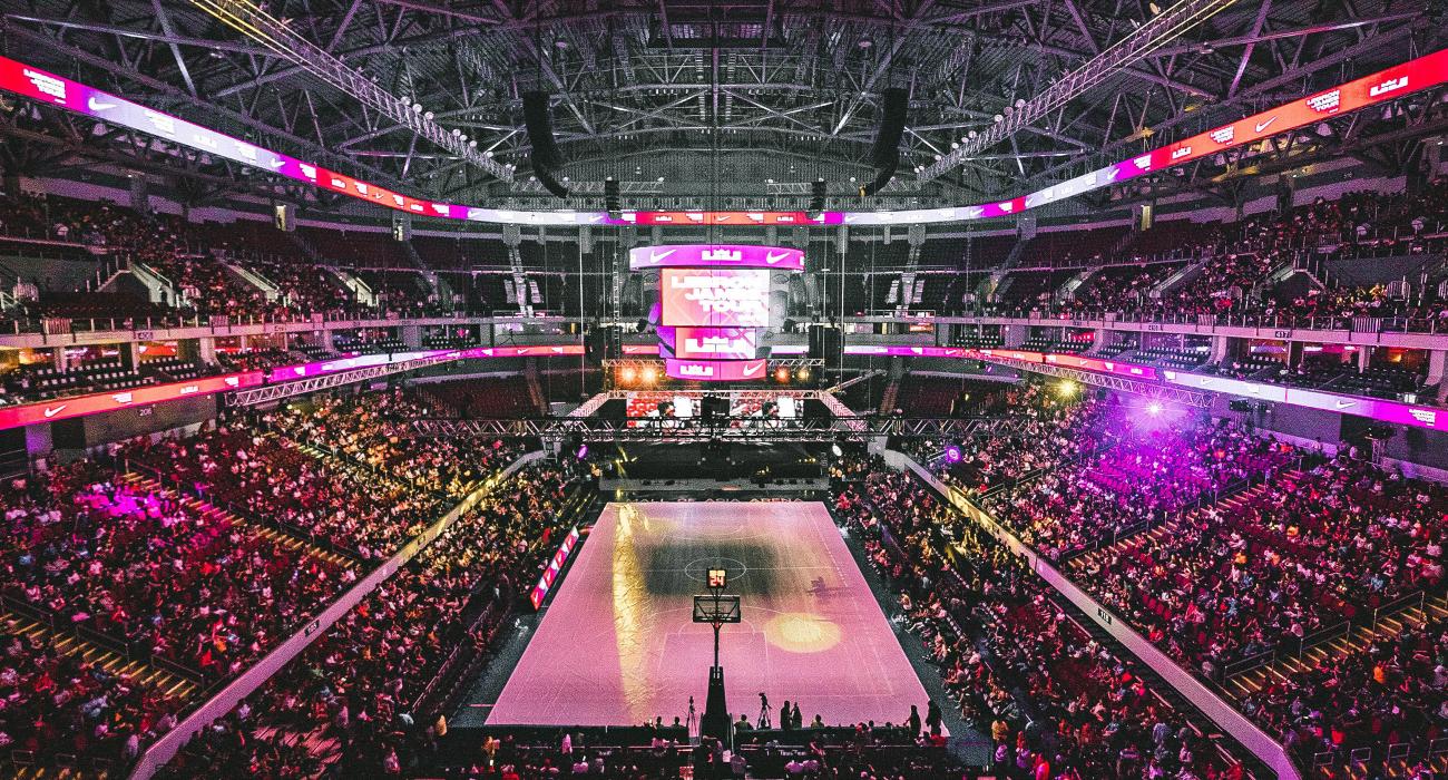 Picture of a full basket ball stadium lit with purple and pink lights